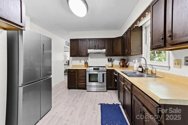 a kitchen with stainless steel appliances granite countertop a refrigerator a sink dishwasher a stove top oven a refrigerator and cabinets