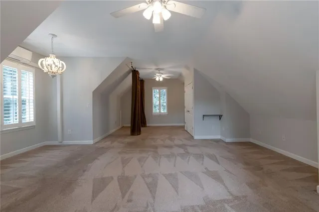 an empty room with a chandelier fan and windows