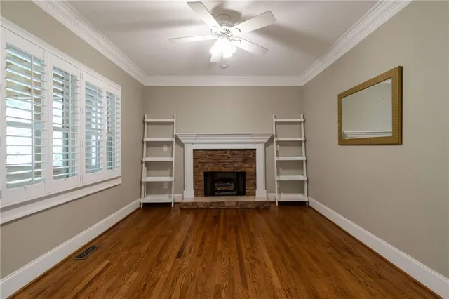 a view of an empty room with wooden floor fireplace and a window