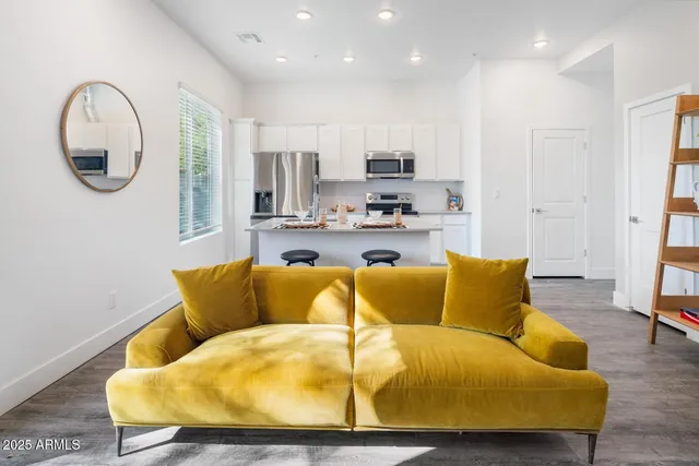 a living room with stainless steel appliances kitchen island a couches and a view of kitchen