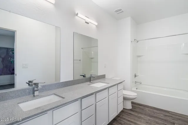 a bathroom with a granite countertop sink a toilet and bathtub