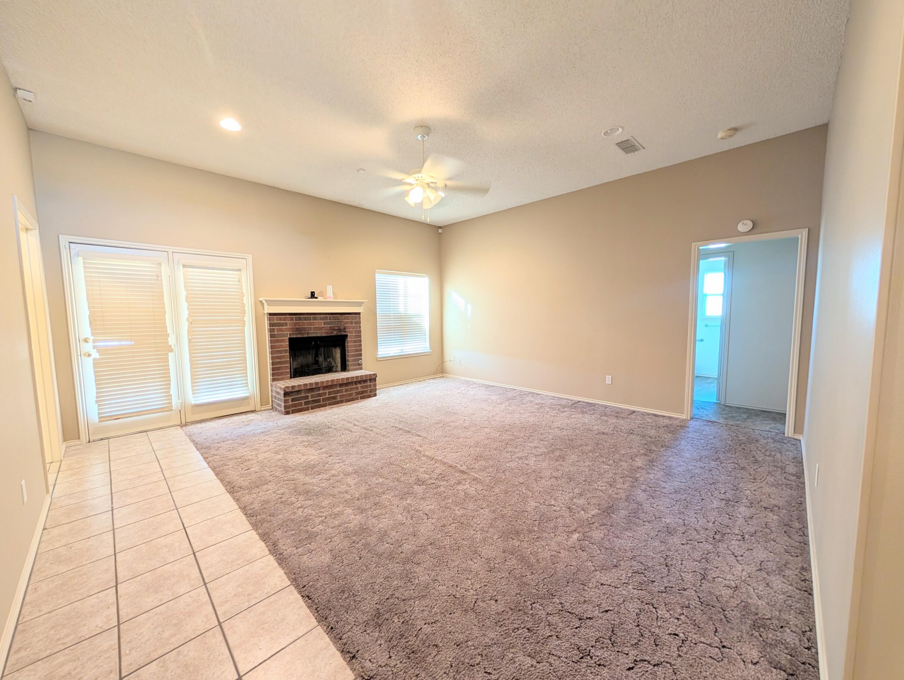 8909 19th Street Lubbock, TX 79407 - Photo 2 of 13 en empty room with windows and fireplace
