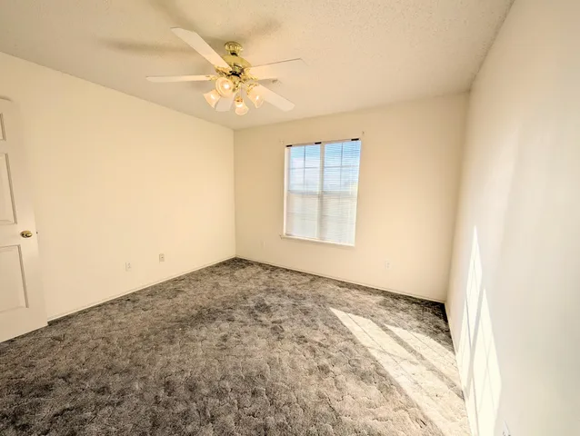 an empty room with wooden floor and fan