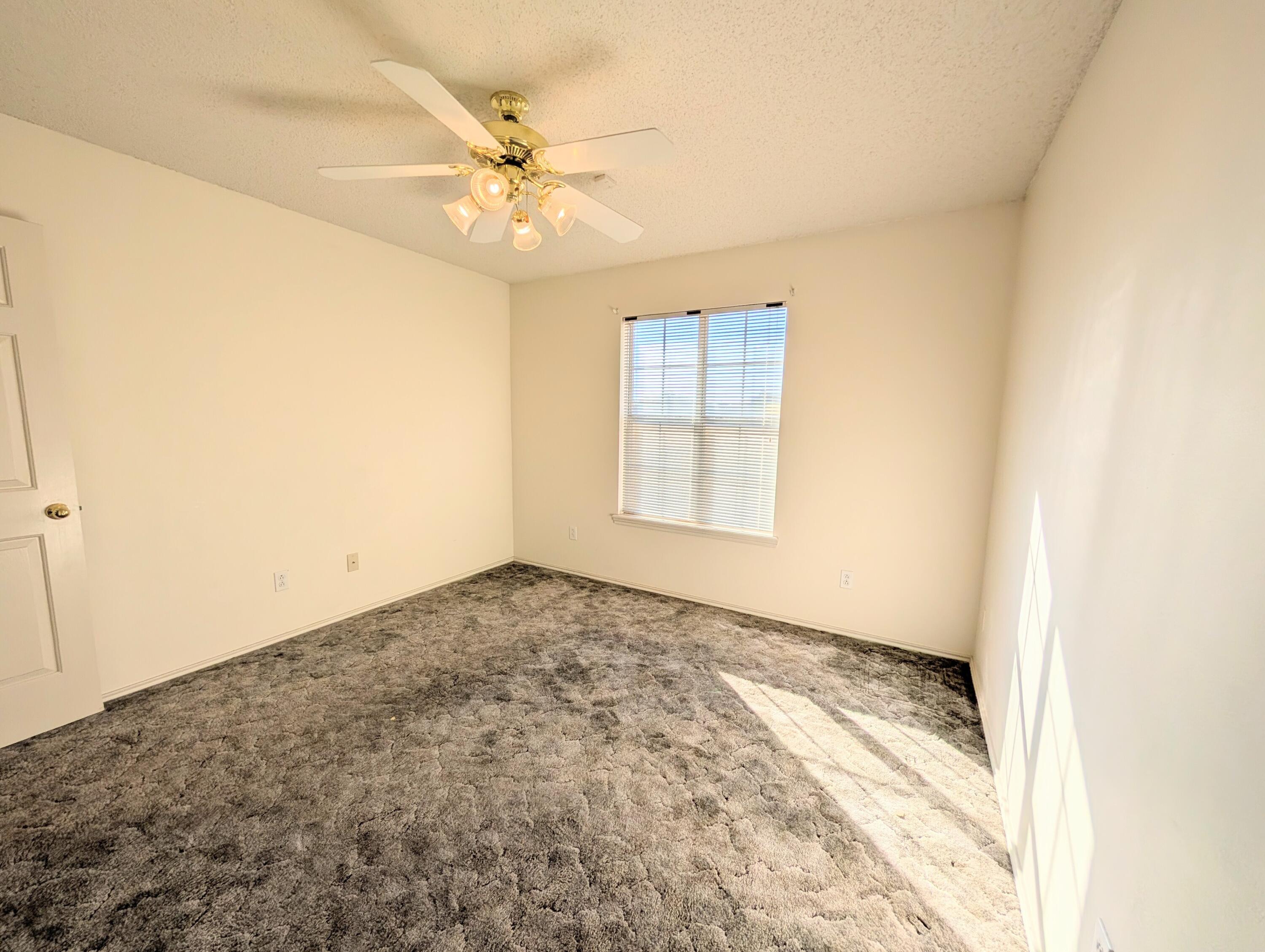 8909 19th Street Lubbock, TX 79407 - Photo 4 of 13 an empty room with wooden floor and fan