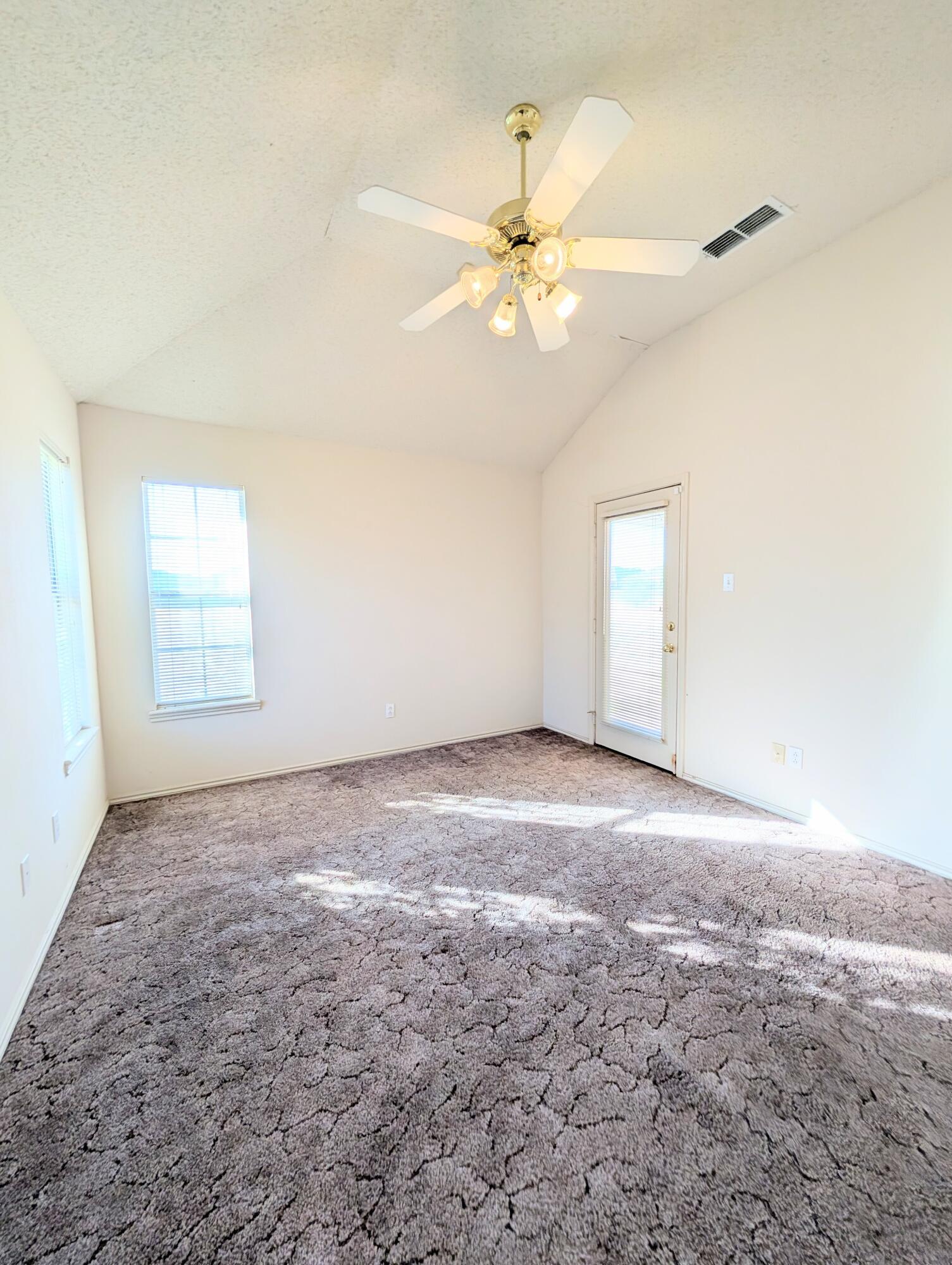 8909 19th Street Lubbock, TX 79407 - Photo 6 of 13 an empty room with windows and fan