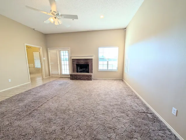 an empty room with windows and fireplace