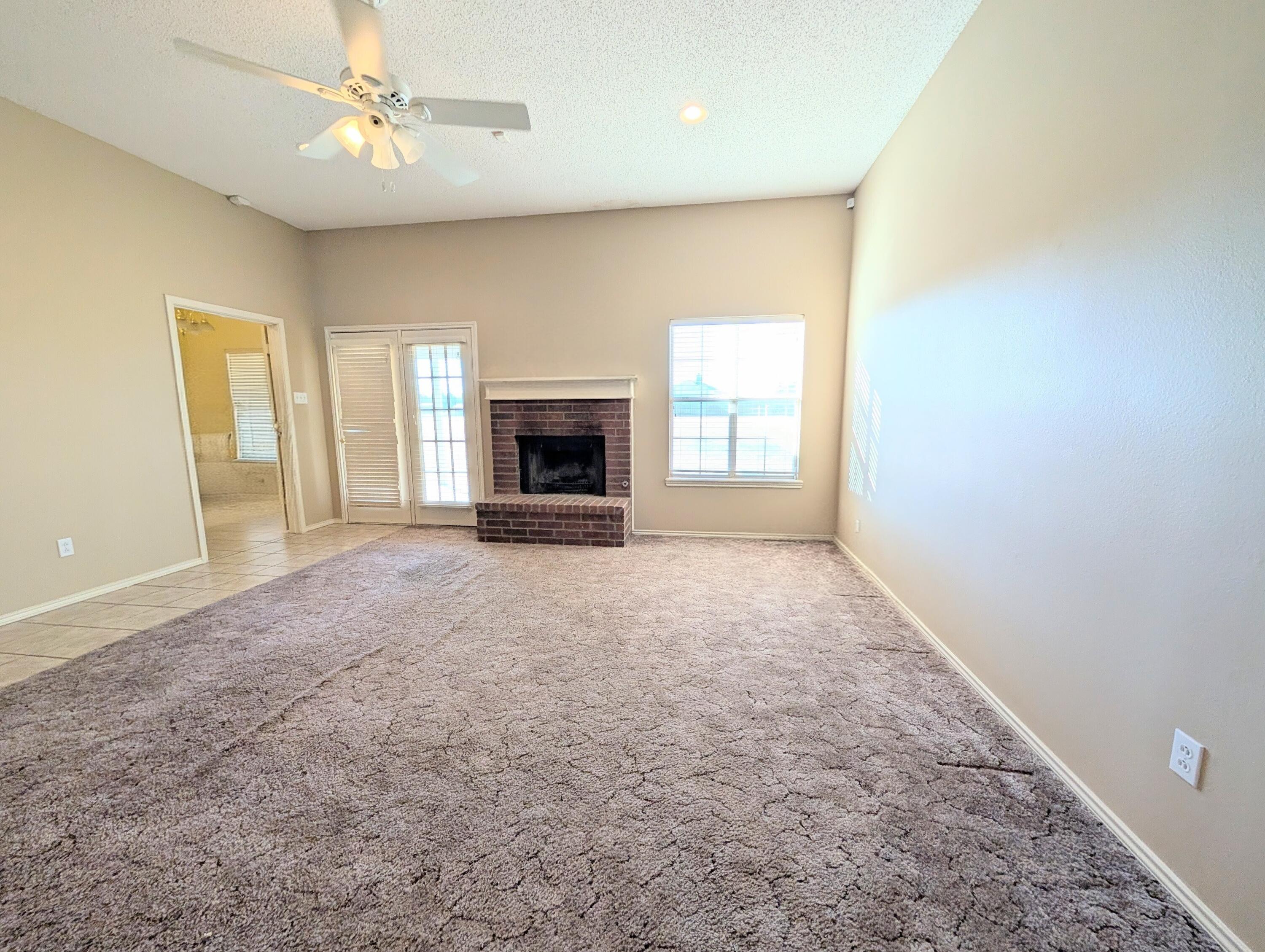 8909 19th Street Lubbock, TX 79407 - Photo 7 of 13 an empty room with windows and fireplace