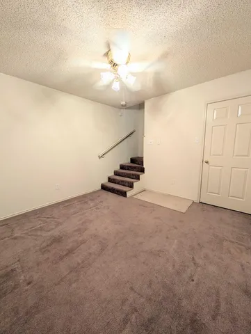 an empty room with staircase and ceiling fan