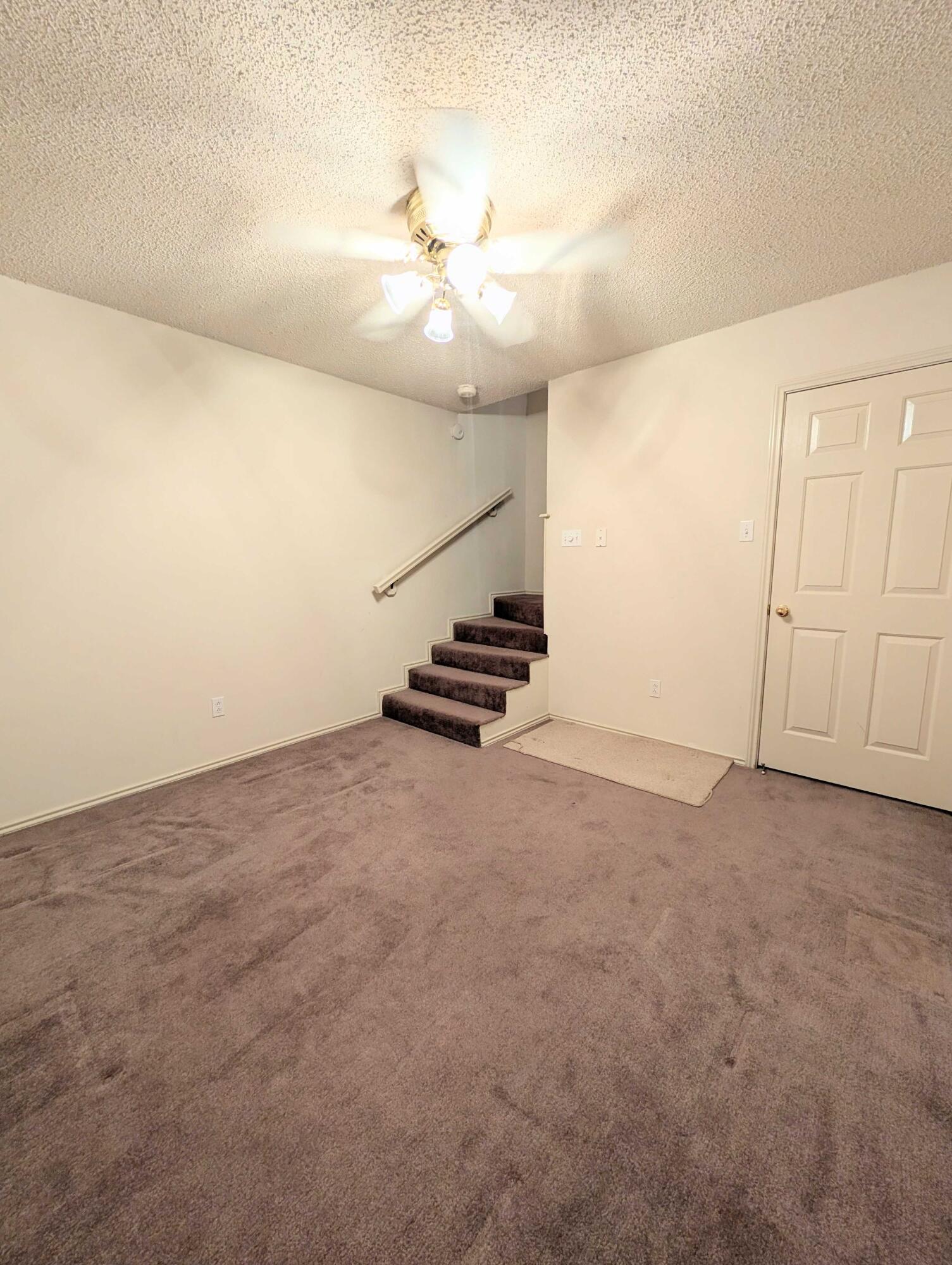 8909 19th Street Lubbock, TX 79407 - Photo 10 of 13 an empty room with staircase and ceiling fan