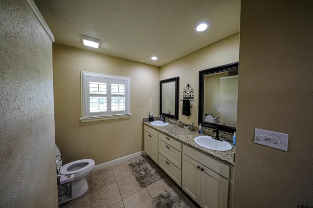 a bathroom with a double vanity sink toilet and mirror
