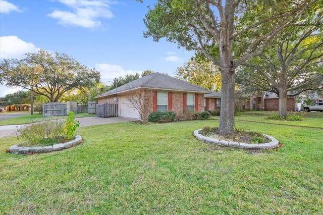 a front view of a house with a garden and trees