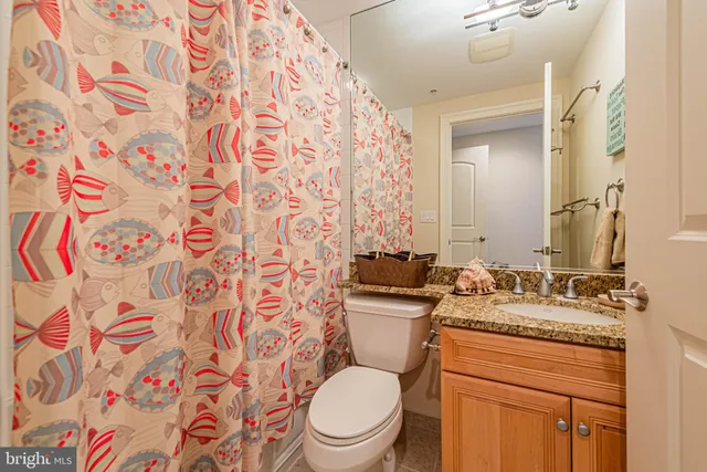 a bathroom with a granite countertop toilet sink and mirror