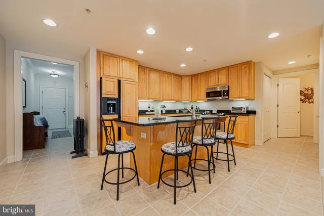 a kitchen with stainless steel appliances kitchen island granite countertop a refrigerator and cabinets