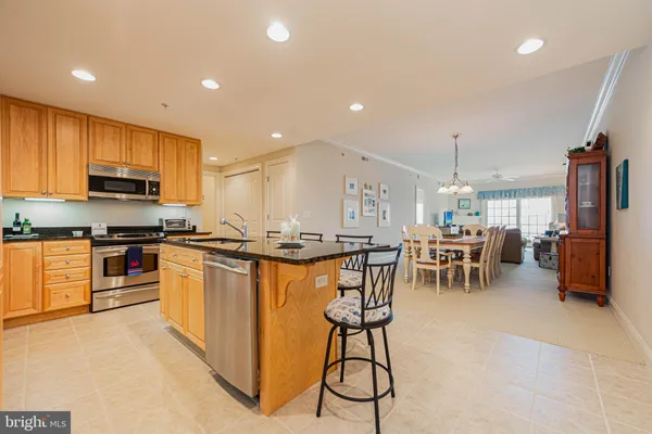 a kitchen with stainless steel appliances kitchen island granite countertop a stove a sink a oven a dining table and chairs with wooden floor