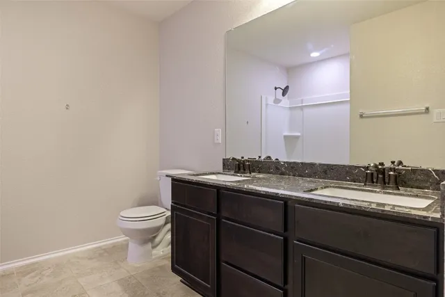 a bathroom with a granite countertop sink a toilet and a mirror