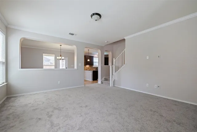 a view of an empty room with a window and kitchen