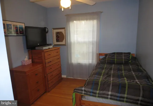 a bedroom with a bed and a chair with the wooden floor