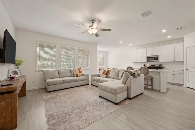 a living room with furniture a ceiling fan and a flat screen tv