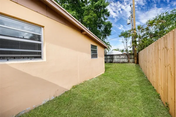 a view of backyard with plants and wooden fence