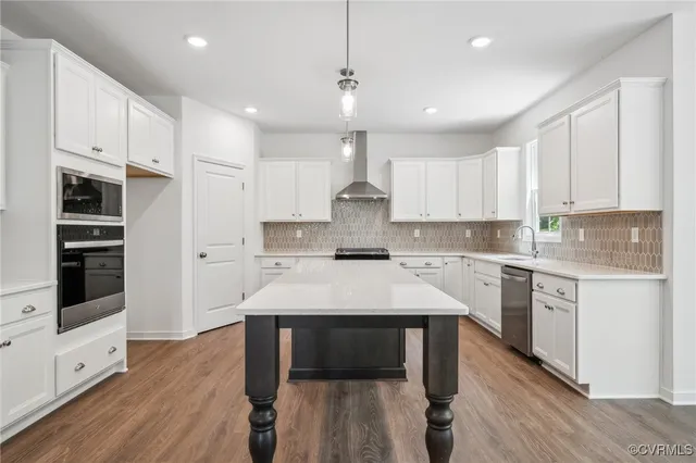 a kitchen with kitchen island a stove a sink a refrigerator and white cabinets with wooden floor