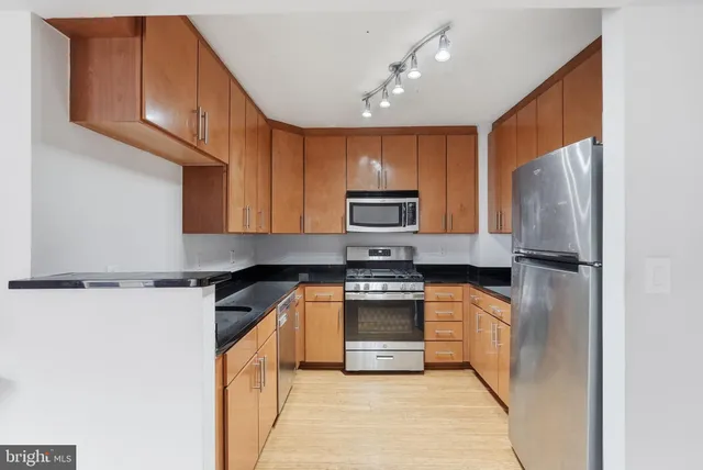 a kitchen with stainless steel appliances granite countertop a refrigerator sink and stove