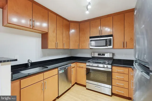 a kitchen with granite countertop cabinets stainless steel appliances and a sink