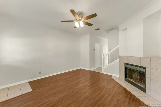 a view of an empty room with wooden floor and a fireplace