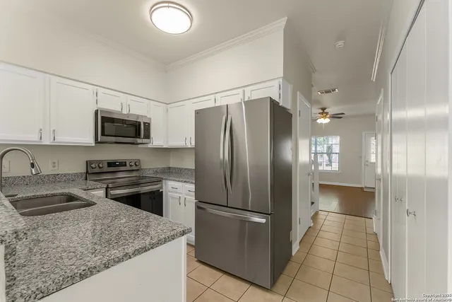 a kitchen with stainless steel appliances granite countertop a refrigerator a stove and a sink