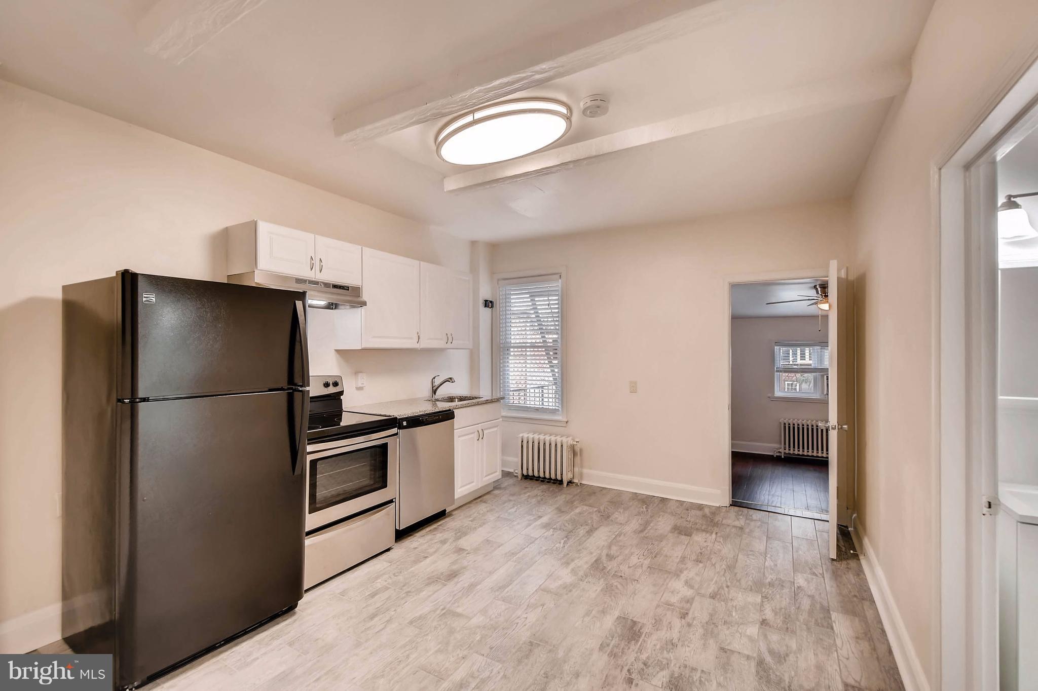 843 North Howard Street, Unit 2 Baltimore, MD 21201 - Photo 2 of 16 a kitchen with a refrigerator a stove top oven and cabinets