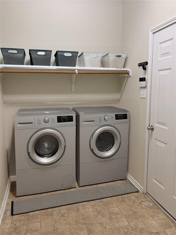3313 Timber Ridge Trail McKinney, TX 75071 - Photo 15 of 20 Washroom featuring washing machine and clothes dryer, stone finish floor, laundry area, and baseboards