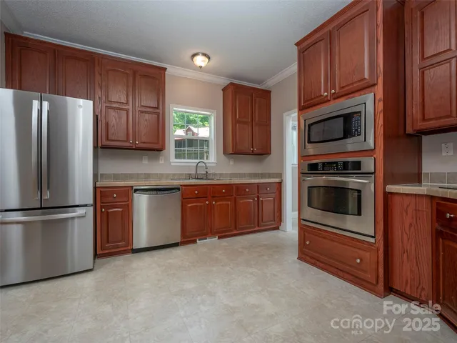 a kitchen with granite countertop wooden cabinets stainless steel appliances and a window