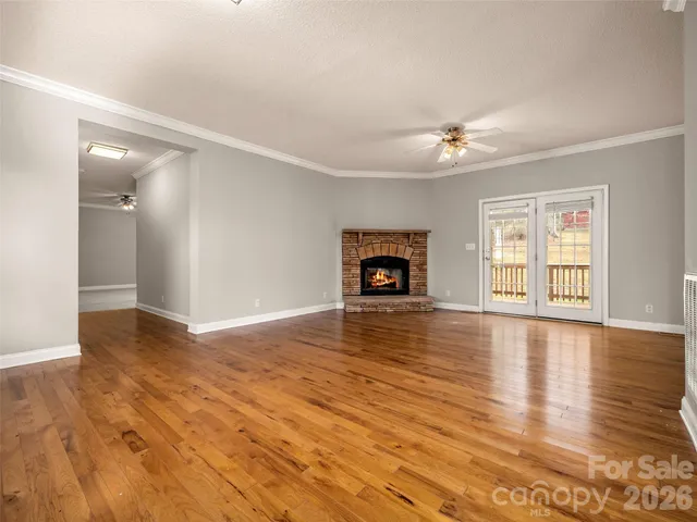 an empty room with wooden floor fireplace and windows