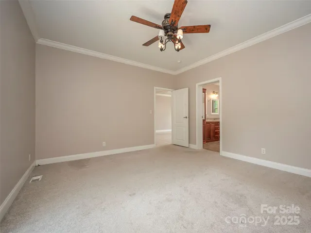 an empty room with chandelier fan and windows