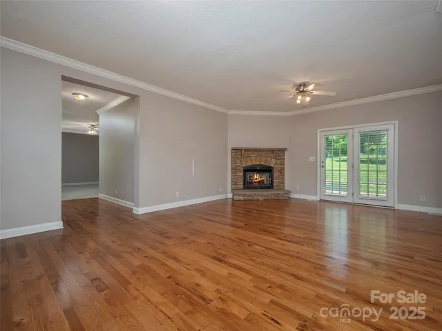 an empty room with wooden floor fireplace and windows