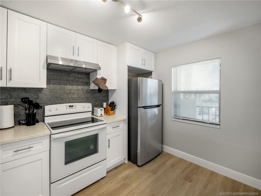 7380 South Ocean Drive, Unit 220 Jensen Beach, FL 34957 - Photo 5 of 33 a kitchen with a refrigerator stove and white cabinets