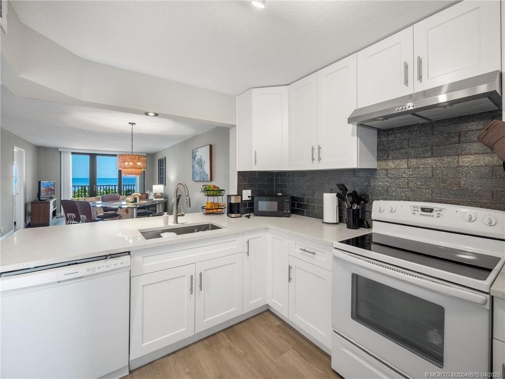7380 South Ocean Drive, Unit 220 Jensen Beach, FL 34957 - Photo 6 of 33 a kitchen with white cabinets and white appliances