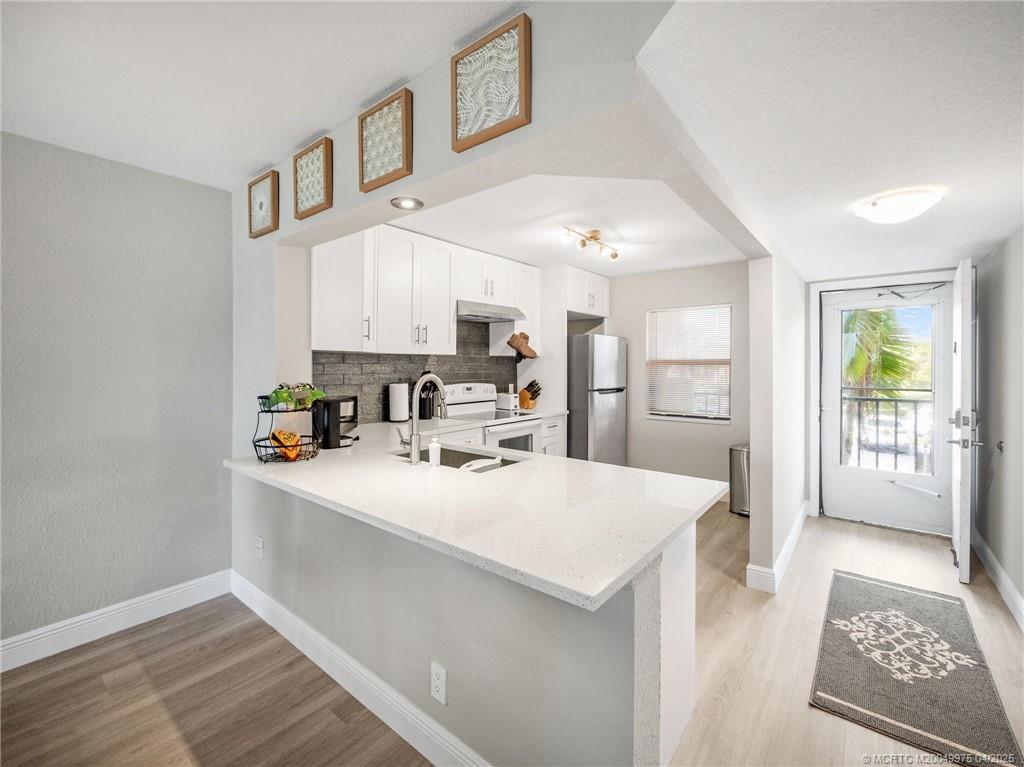 7380 South Ocean Drive, Unit 220 Jensen Beach, FL 34957 - Photo 7 of 33 a large white kitchen with sink and refrigerator