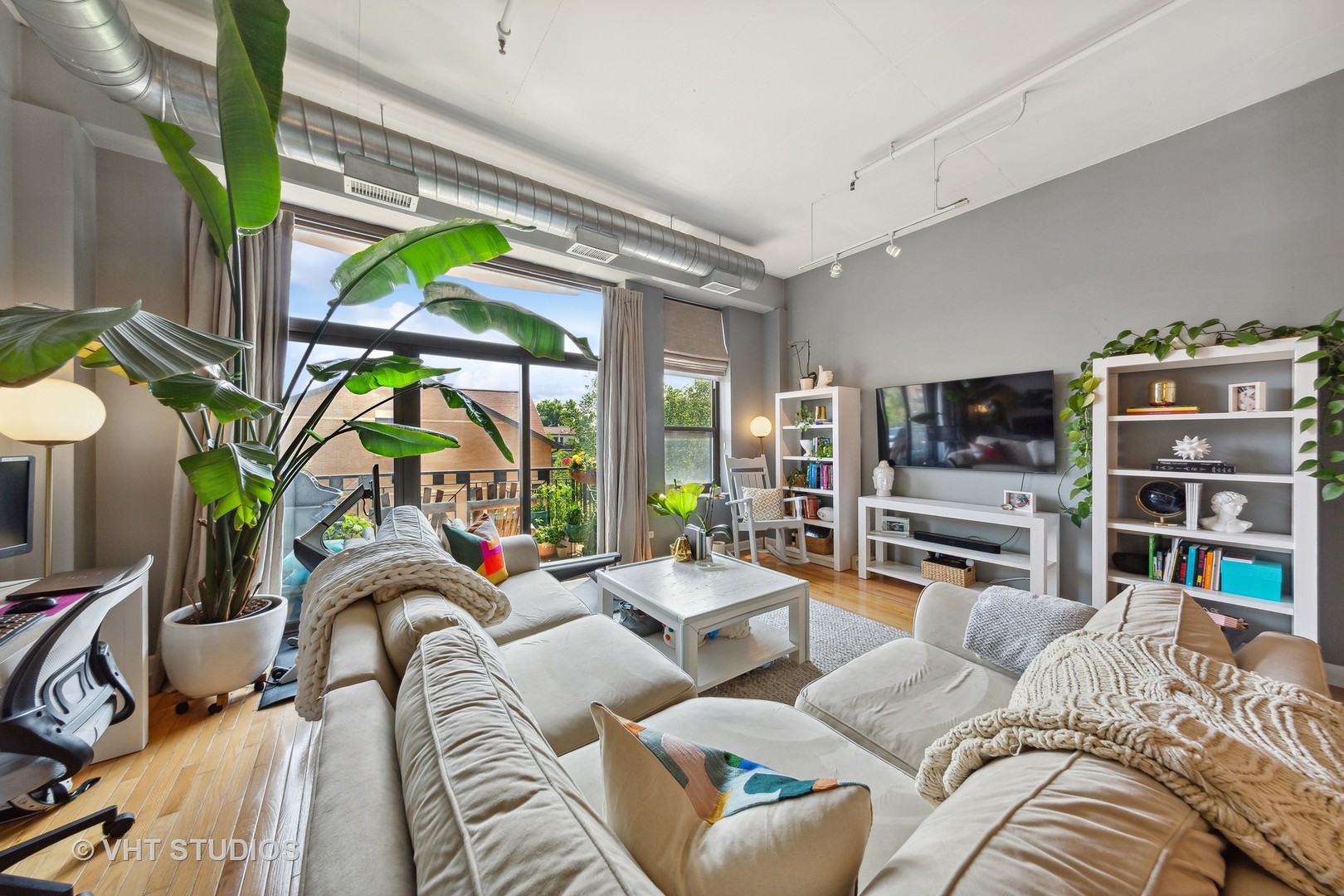 1301 West Madison Street, Unit 314 Chicago, IL 60607 - Photo 6 of 14 a living room with furniture a flat screen tv and a floor to ceiling window