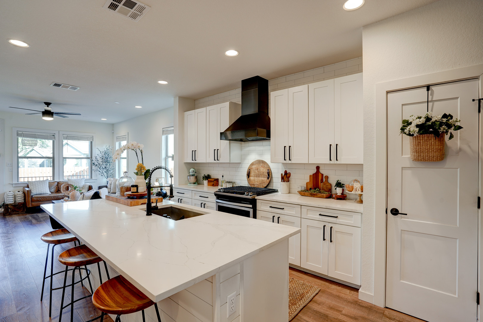 2240 Ringstaff Road Leander, TX 78641 - Photo 6 of 25 Kitchen featuring a large island with a built-in sink, white shaker cabinetry, stone countertops, and a subway tile backsplash