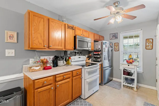 a kitchen with a refrigerator a stove a sink cabinets and a window