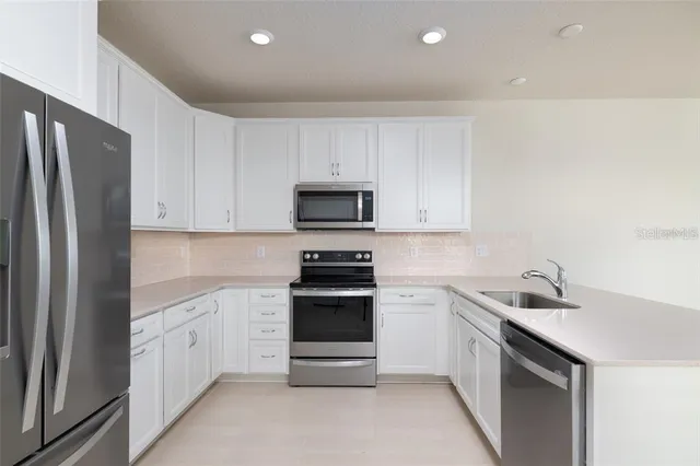 a kitchen with white cabinets and stainless steel appliances