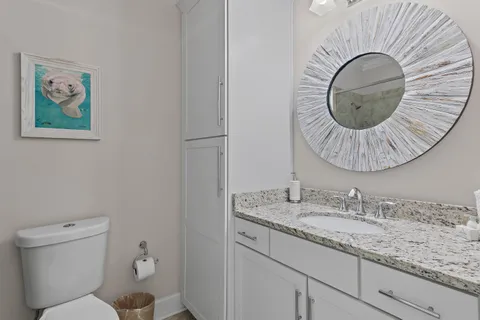 a bathroom with a granite countertop toilet a sink and mirror