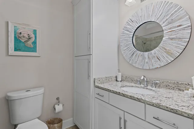 a bathroom with a granite countertop toilet a sink and mirror