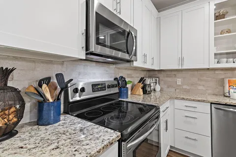 a kitchen with granite countertop a stove top oven microwave and cabinets