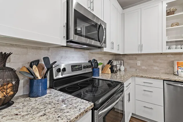 a kitchen with granite countertop a stove top oven microwave and cabinets