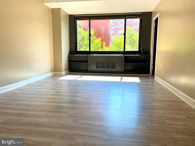 a view of an empty room with wooden floor and a window