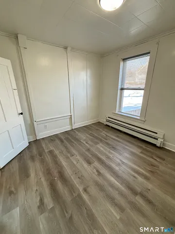 a view of an empty room with wooden floor and closet