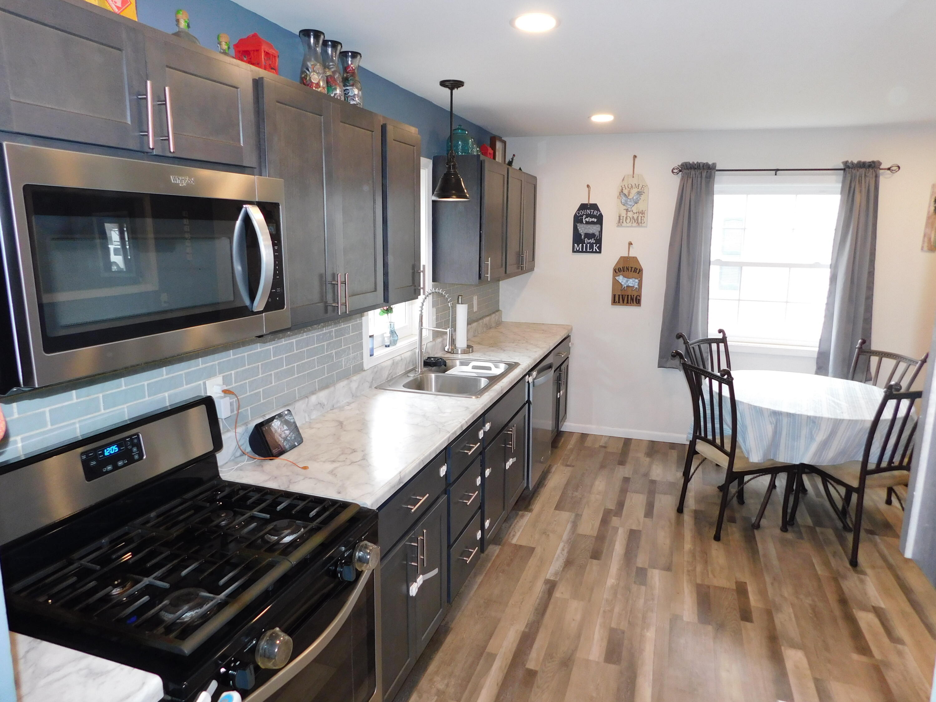 2347 Sloan Street Portage, IN 46368 - Photo 9 of 19 a kitchen with stainless steel appliances a stove a sink dishwasher a microwave oven and a dining table with wooden floor