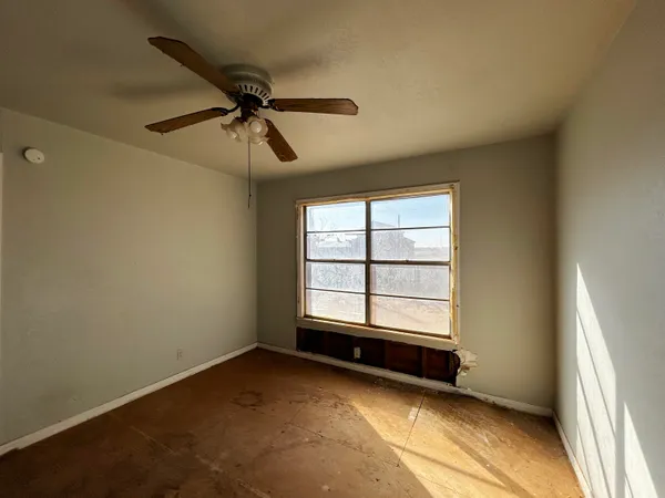 an empty room with windows and fan