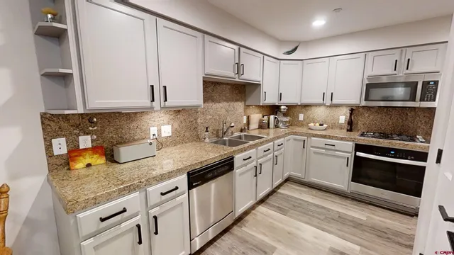 a kitchen with granite countertop a sink stainless steel appliances and white cabinets